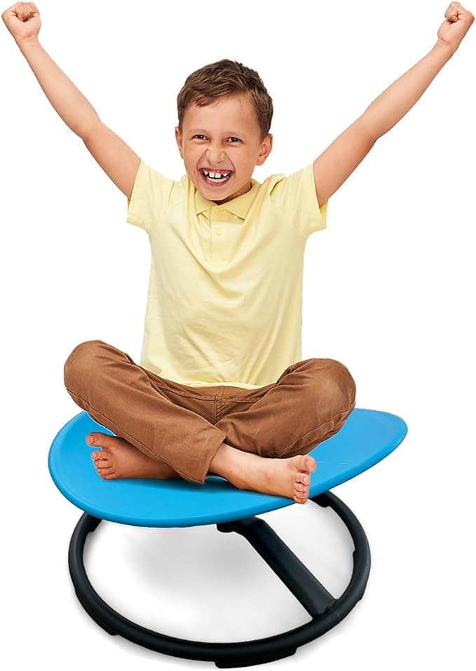 Smiling boy sitting cross-legged on blue sensory spinning chair, arms raised in excitement