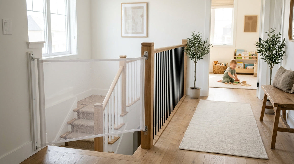 A mesh retractable gate screwed to the wall and newel post across the top of a carpeted staircase