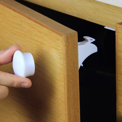 Parent holding magnetic key replacement against wood drawer front to disengage hidden cabinet lock inside