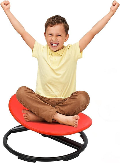 Smiling boy sitting cross-legged on red 360° sensory spinning chair, arms raised in triumph
