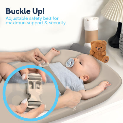Parent buckling adjustable safety belt across baby lying on beige Nest Eva changing pad, buckle close-up inset